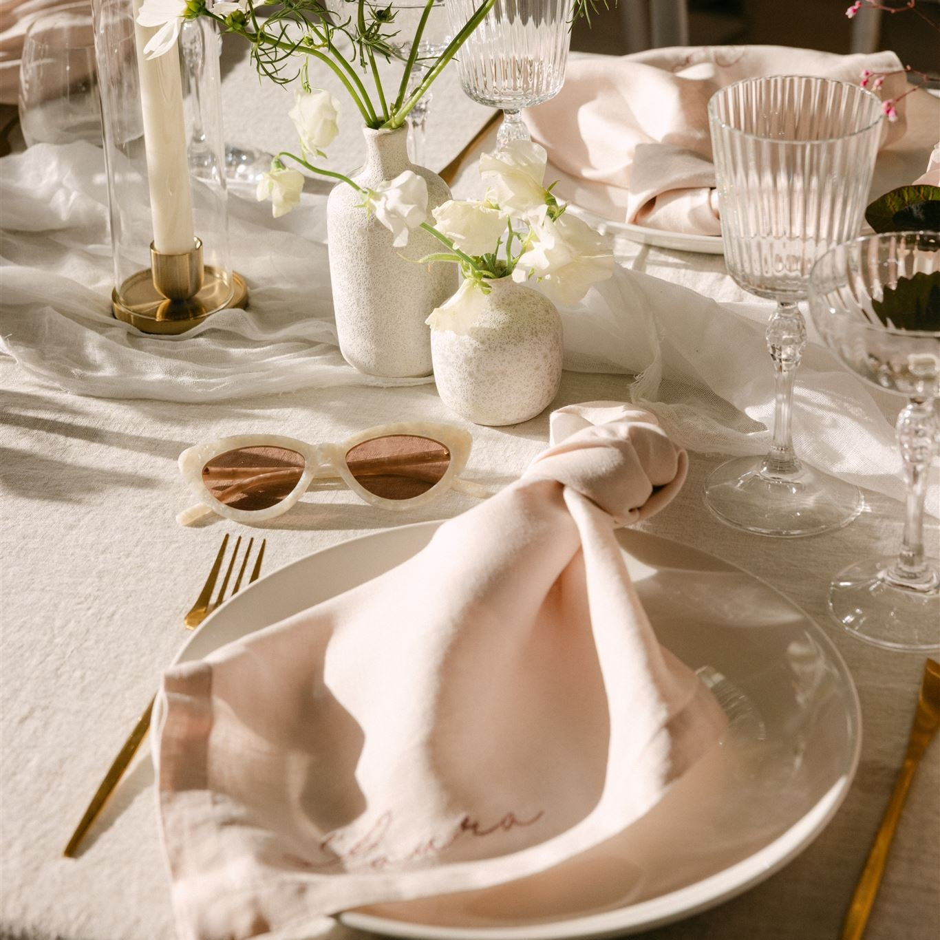 Blush personalised napkin embroidered with the name Laura at an elegant wedding place setting with gold cutlery and crystal glassware