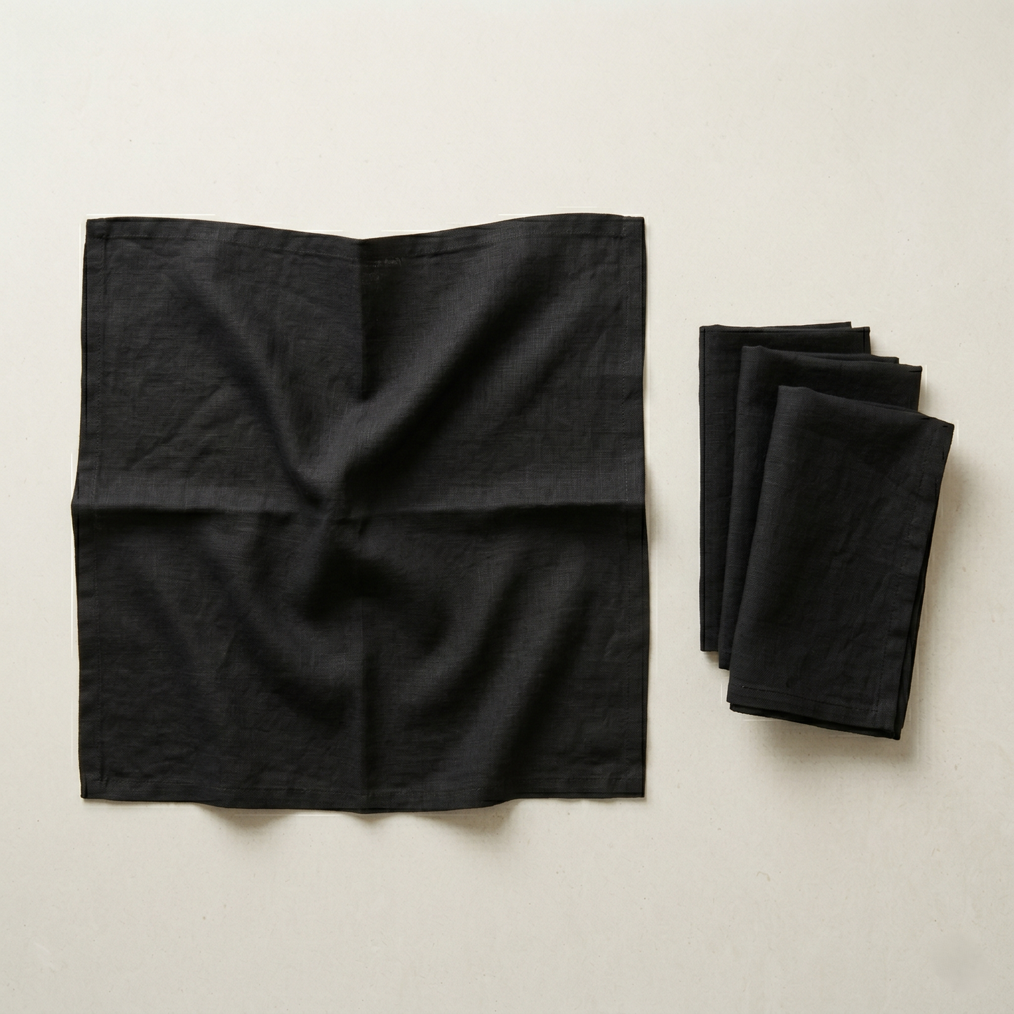 Stack of four folded black plain linen napkins in soft matte pure linen