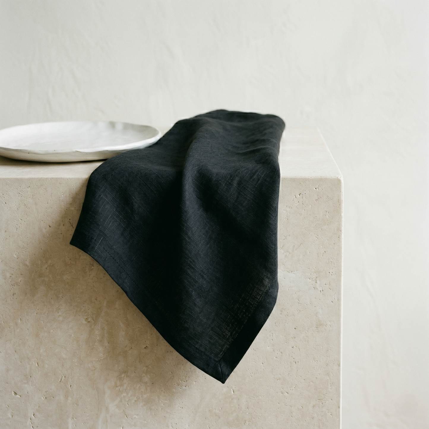 Black plain pure linen napkin draped to show its soft, matte slubby weave