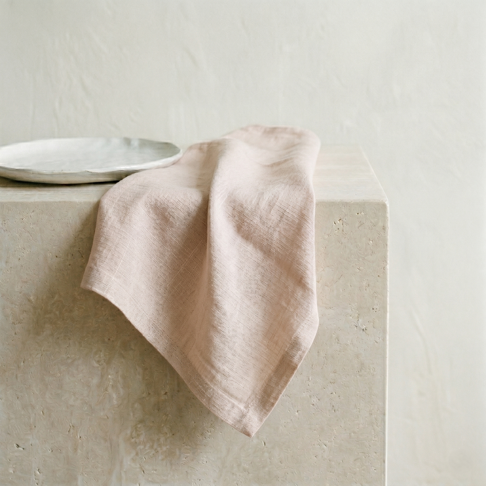 Blush plain pure linen napkin draped to show its soft, slubby warm-pink weave