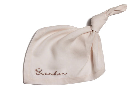 Personalised blush linen napkin with the name Brandon embroidered in dark pink script